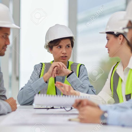 189469704-tout-planifier-un-groupe-de-jeunes-travailleurs-de-la-construction-assis-autour-de-la-table-de-la